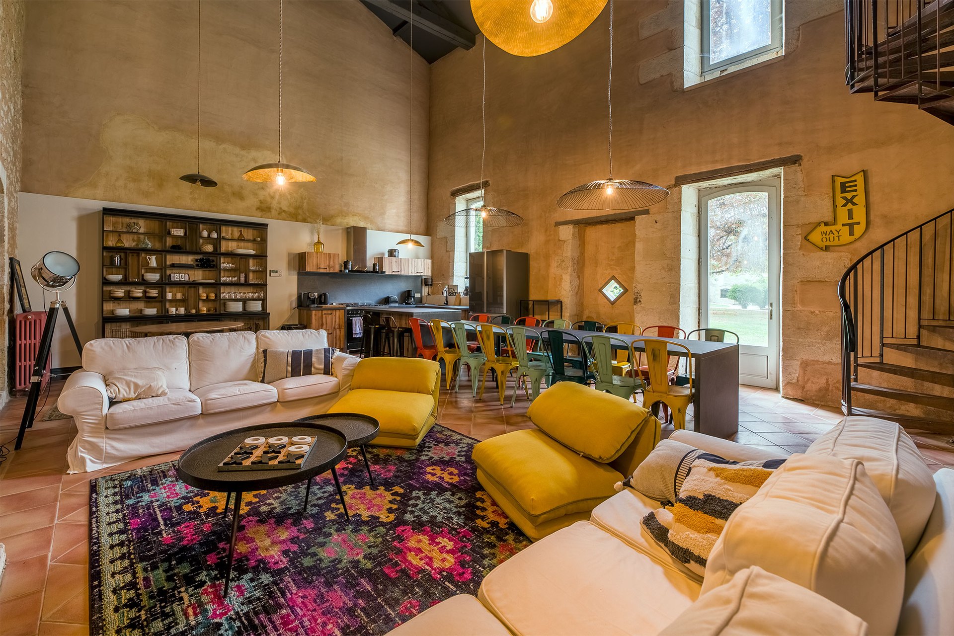 The open-plan living room with yellow armchairs and a stone staircase
